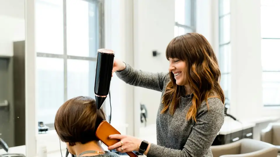 A hairdresser blow-drying a client in a bright modern salon