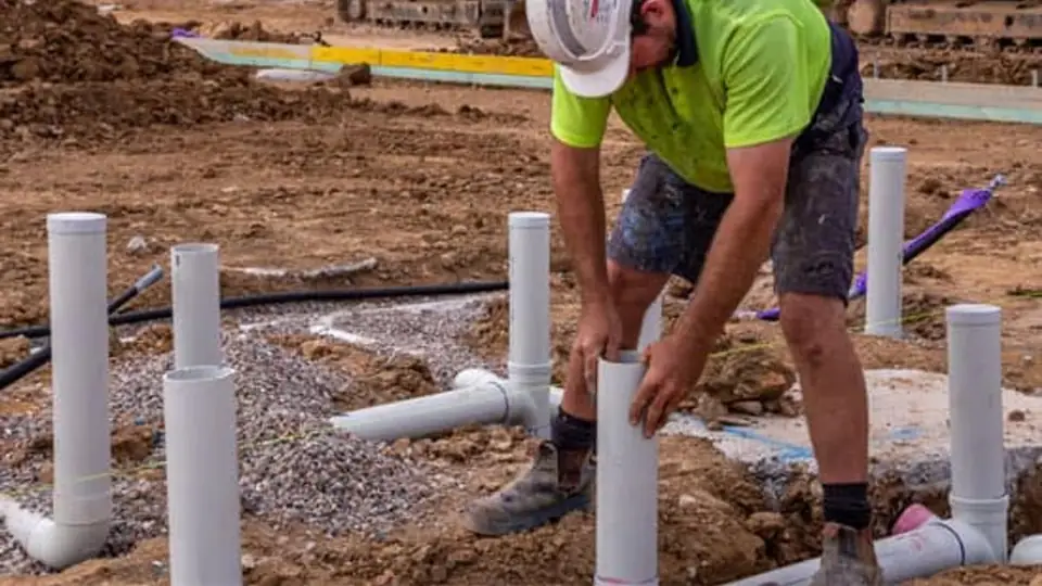 A plumber laying out PVC pipes on a new building site